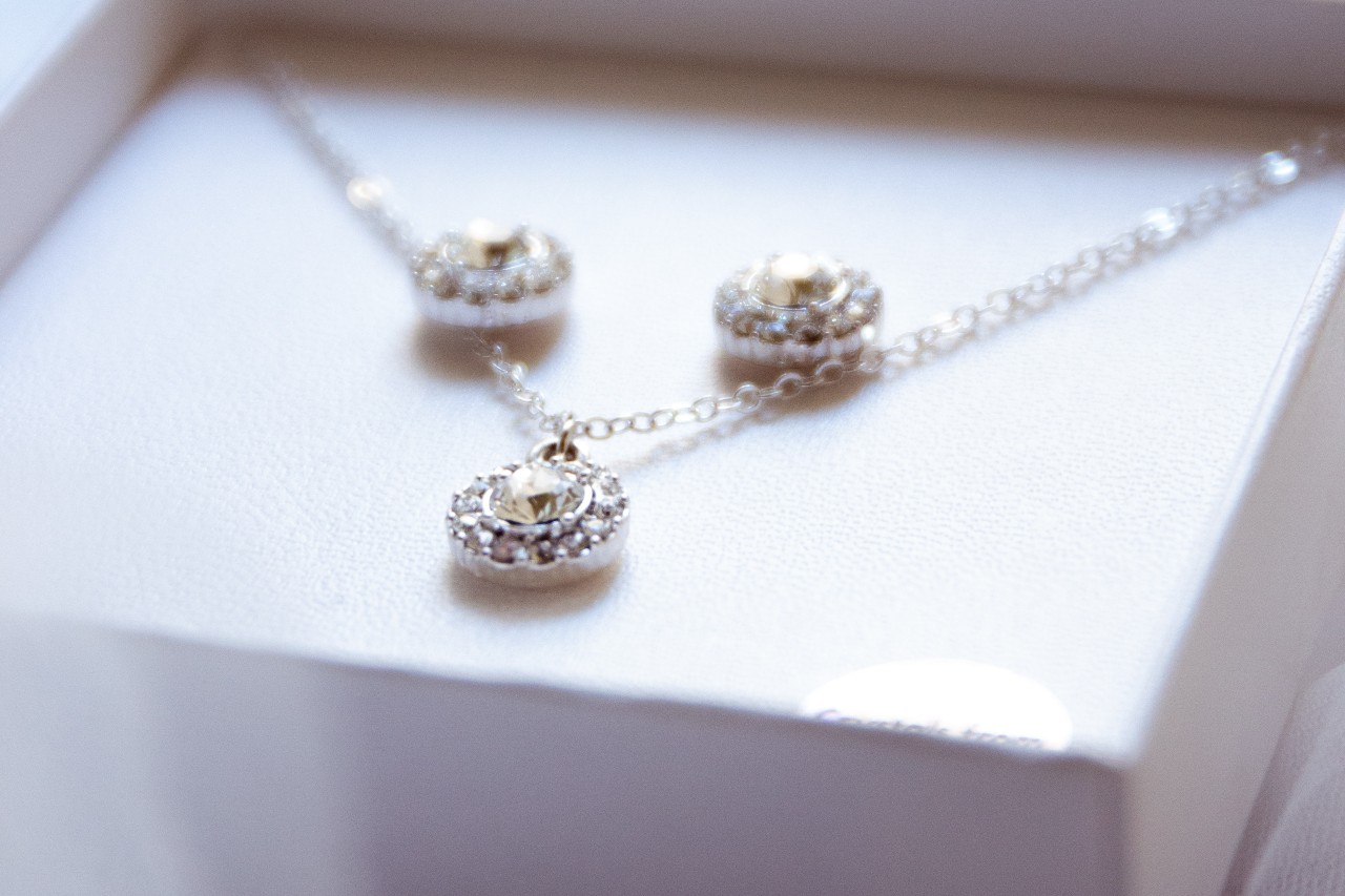 a diamond necklace and stud earrings sit in a gift box.