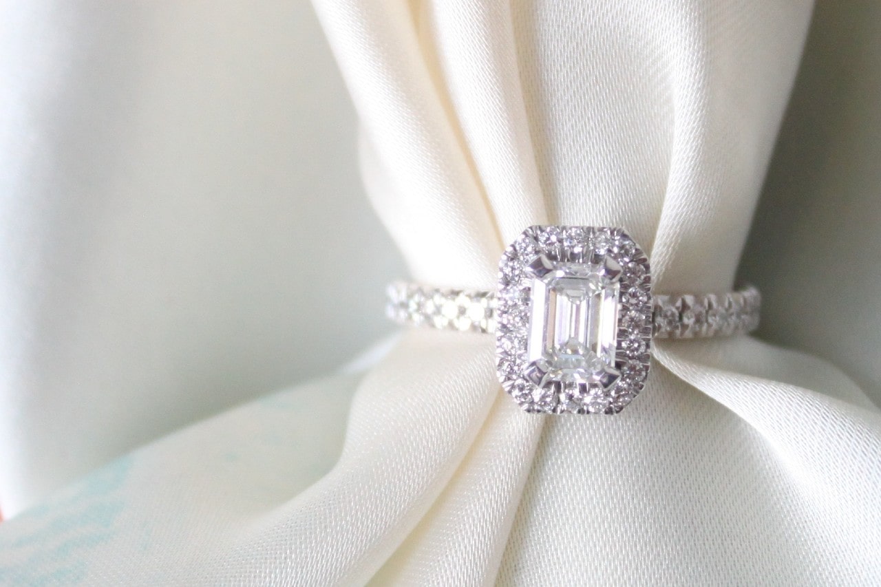 a white gold halo engagement ring with white fabric threaded through its band