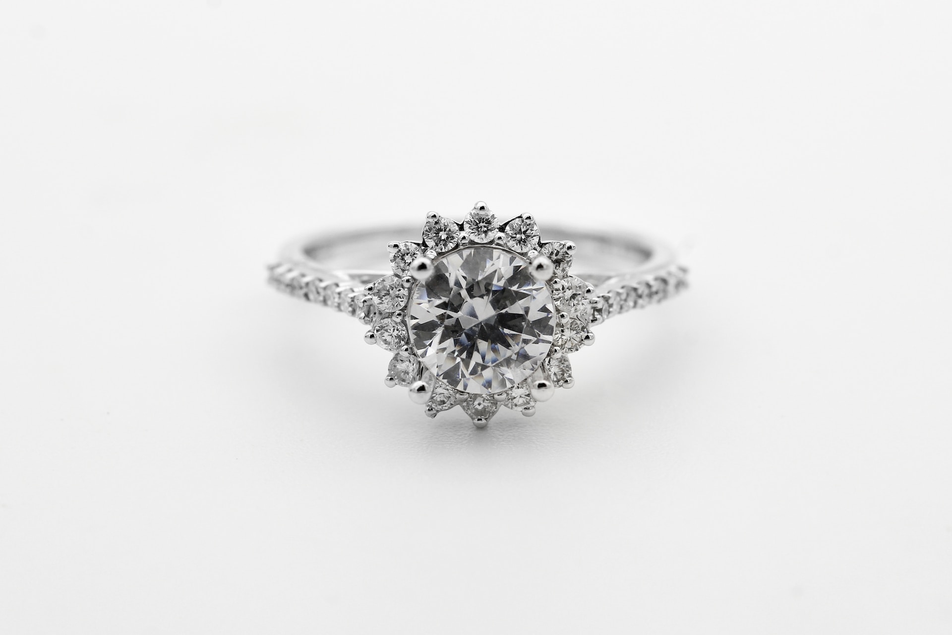 a white gold diamond halo engagement ring against a white background