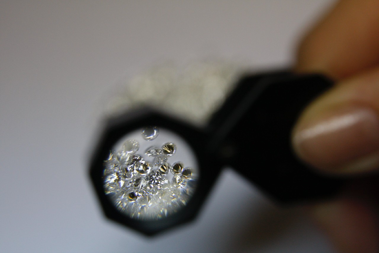 a person looking through a magnifying glass at a cluster of diamonds