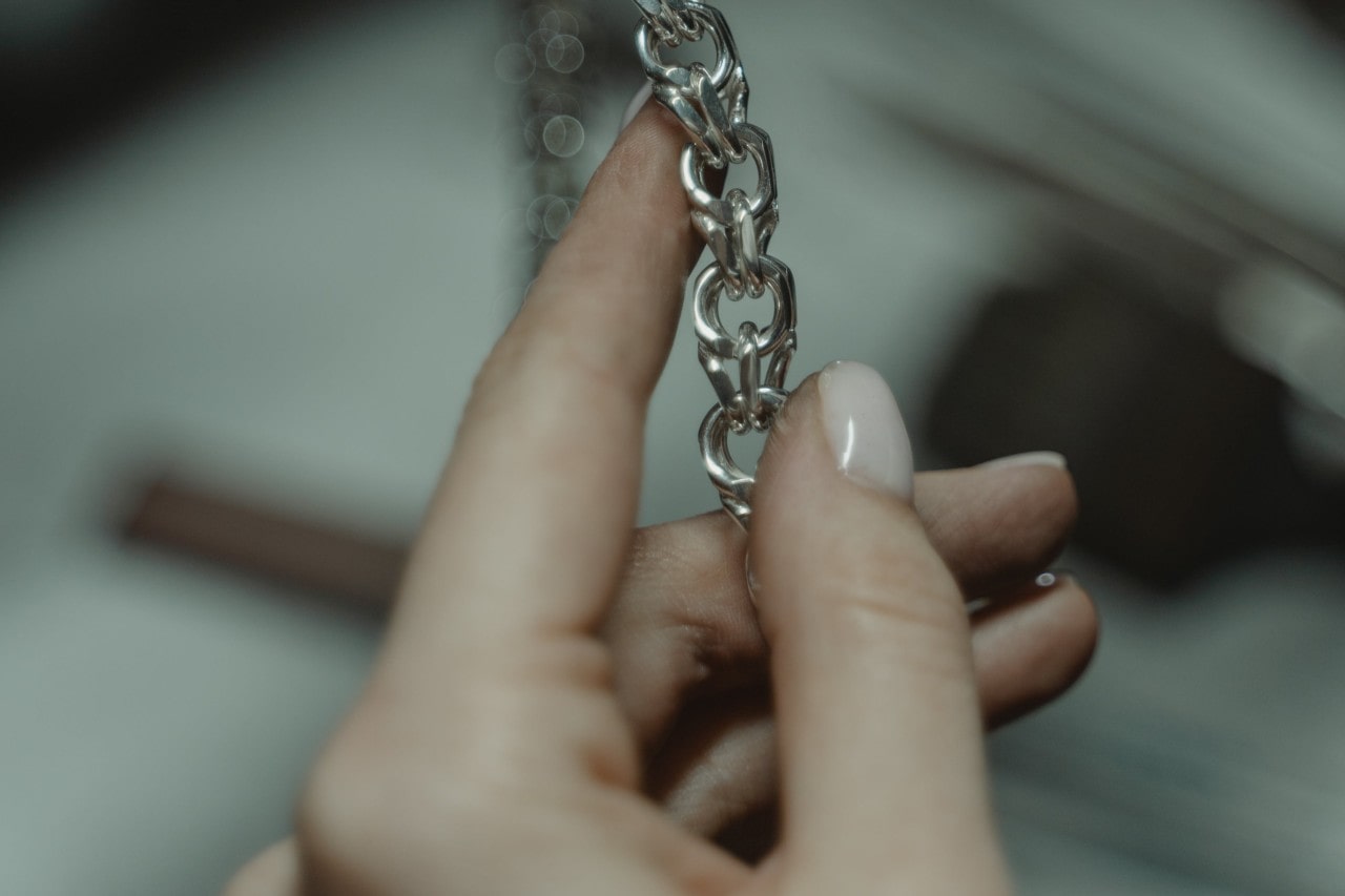 a jeweler’s hand holding a silver chain