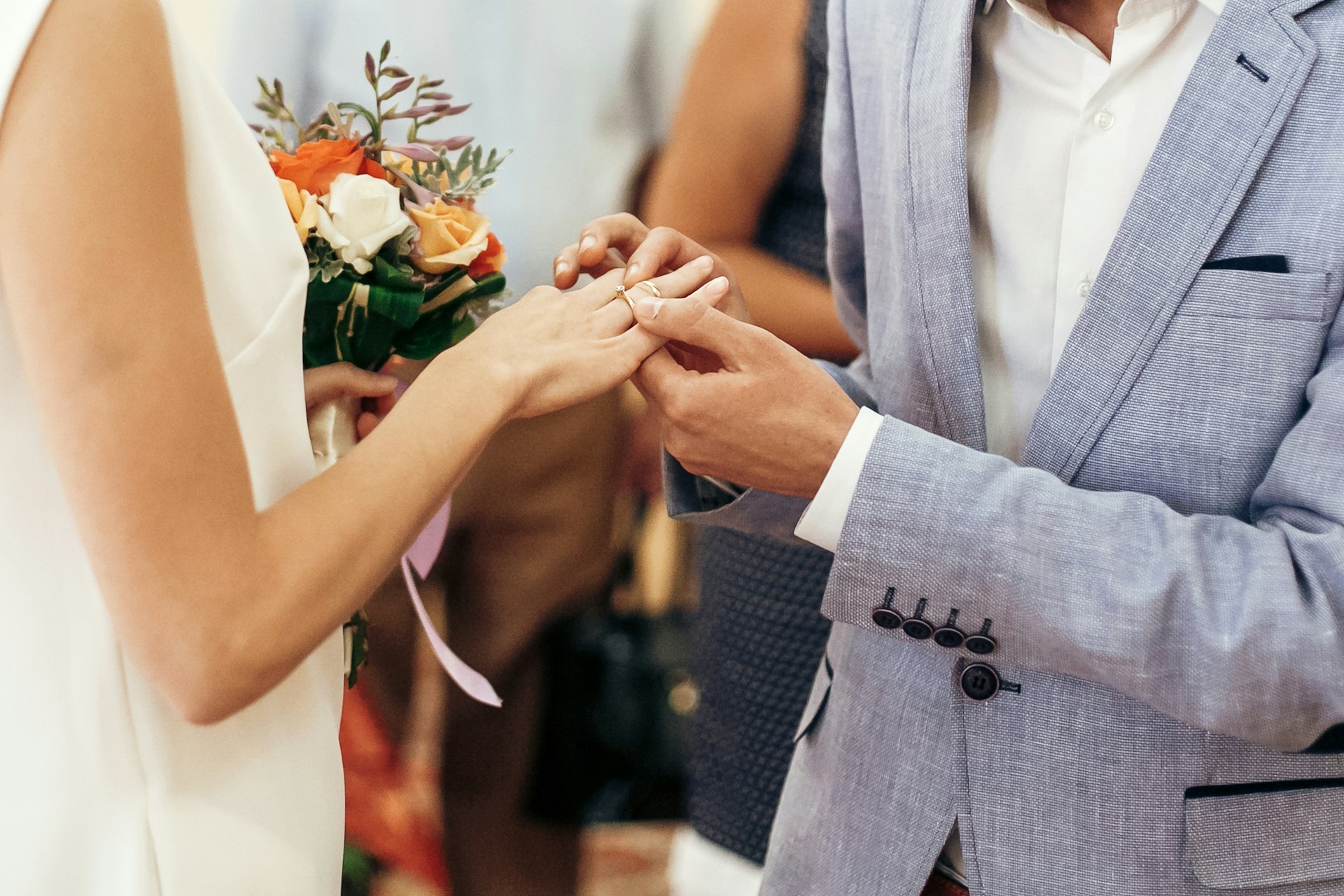 A man putting the wedding band on a bride’s hand during their wedding ceremony.