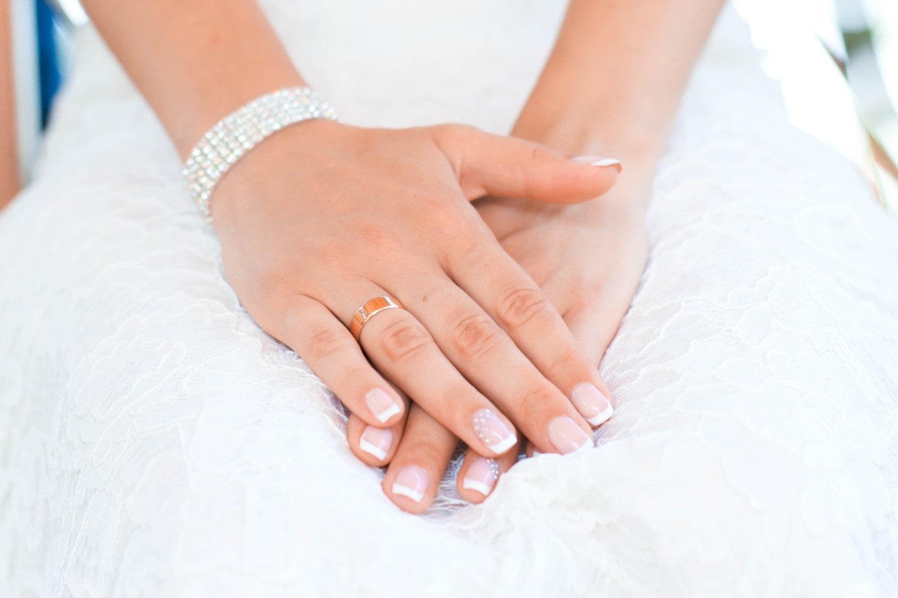 A close-up of a bride’s hands on her lap, a glistening diamond bracelet on her wrist.
