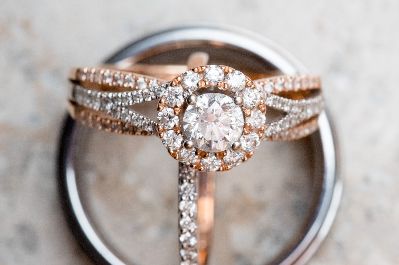 A close-up of a stunning halo engagement ring displayed with two wedding bands. A close-up of a stunning halo engagement ring displayed with two wedding bands.