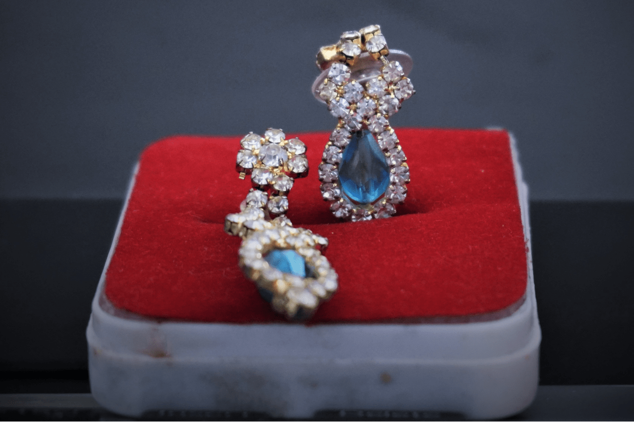 a pair of blue topaz and diamond earrings sit in a jewelry box.