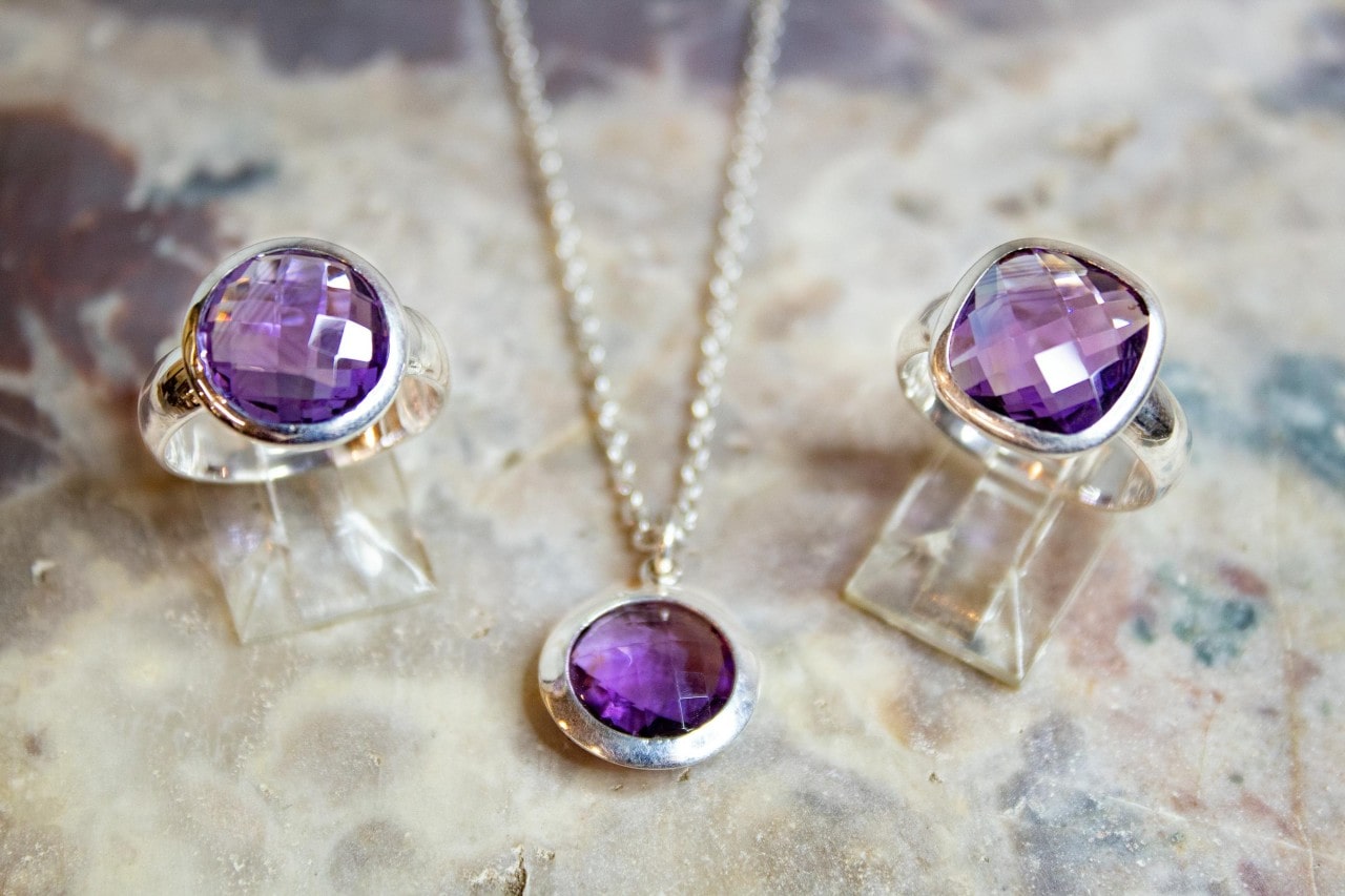 an amethyst pendant and rings sit in a display.